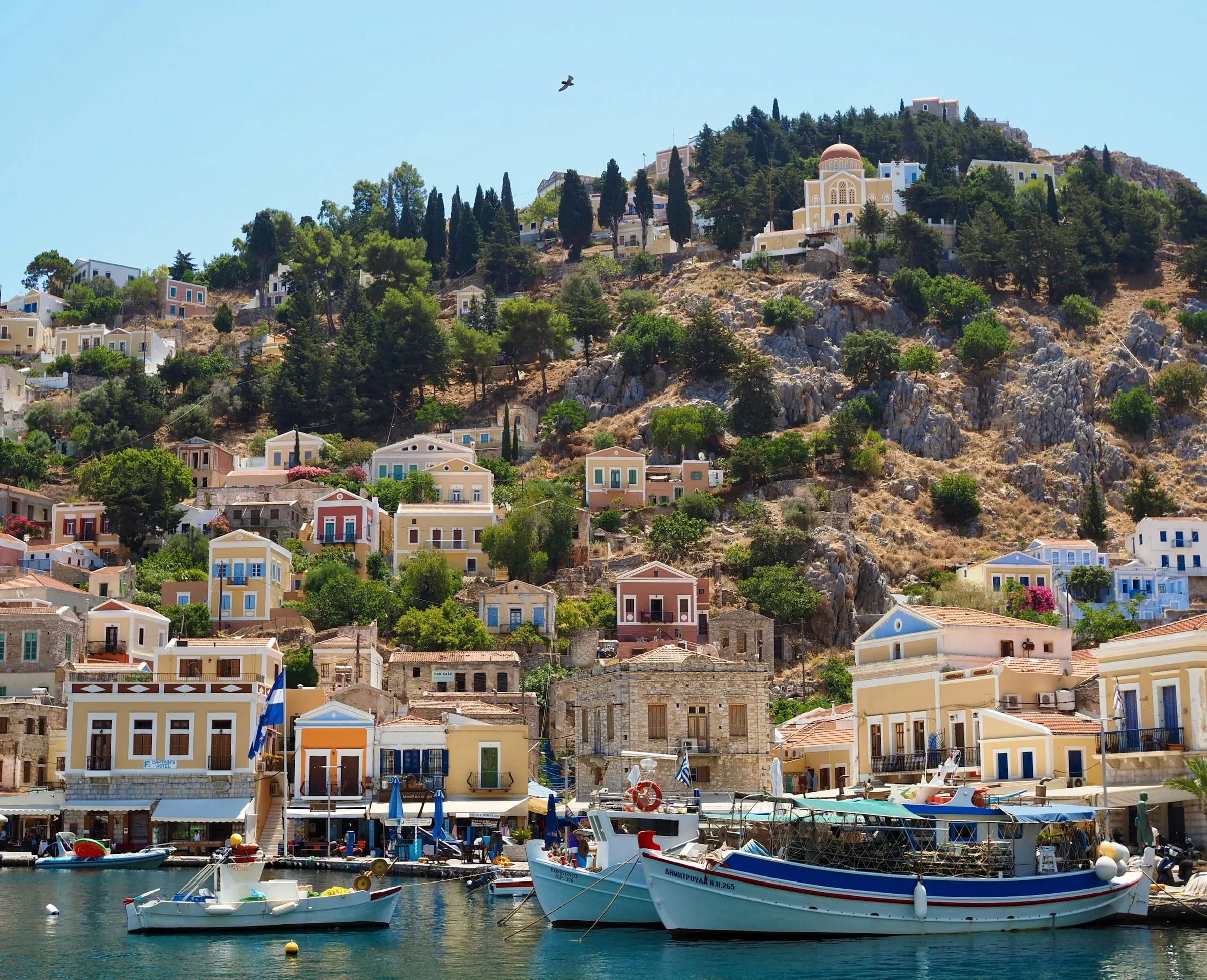 Un caïque devant les maisons colorées du port de Symi