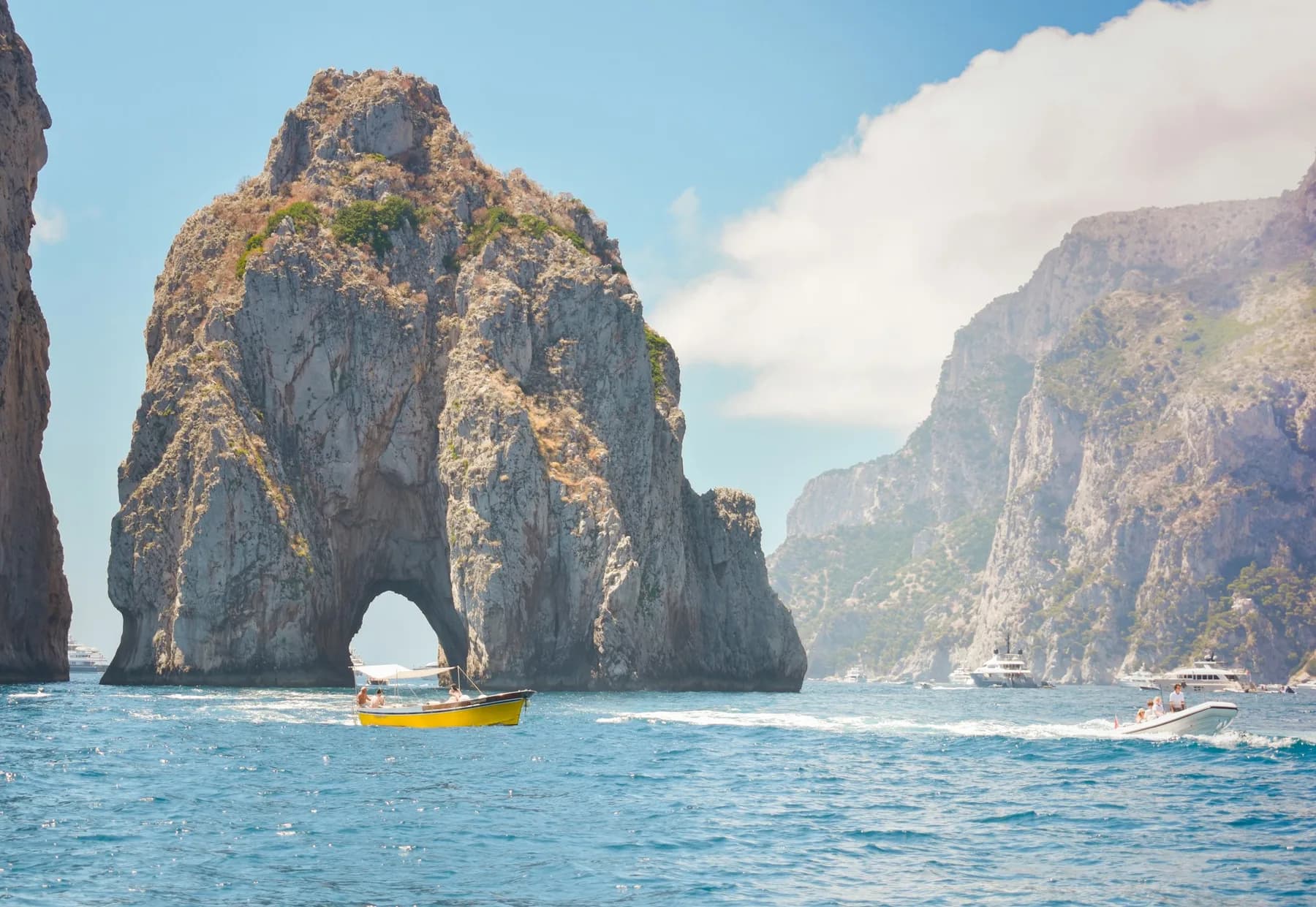 Bateau passant sous l'arche des Faraglioni, au large de Capri